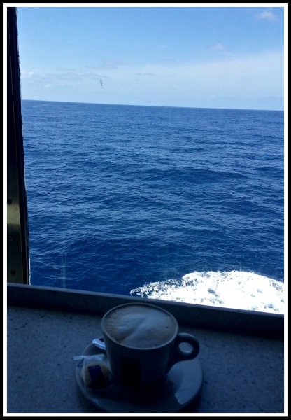 A Cappuccino on a window seat looking out over a beautiful blue seaat sea