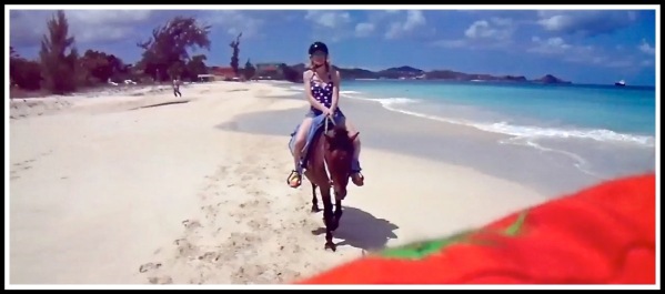 Photo of Sarah on her horse riding across stunning beach landscape with my orange shirt at the bottom as i took the photo over my shoulder