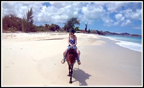 Sarah on her horse looking inland as she rides across the stunning beach