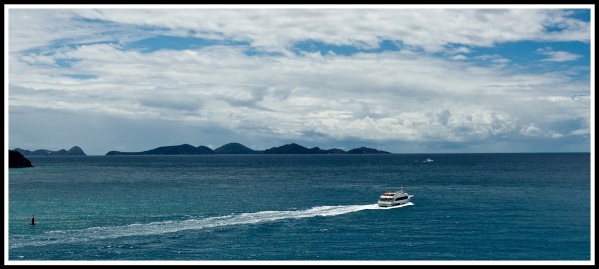 A boat leaving its stream from left to right with the coastline behind it