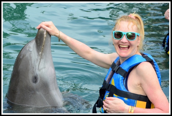 Sarah now looking at the camera with a huge smile on her face, whist still touching the dolphins nose