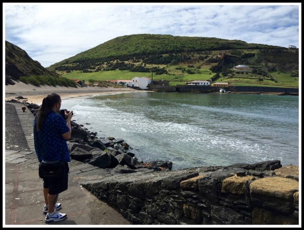 Me stood on the left with volcanic rock beach all around and a view of the bay