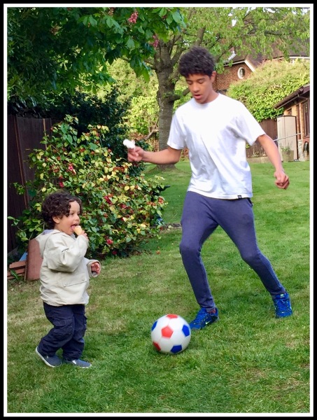Vini playing football with his brother Raffy whilst holding an ice-cream