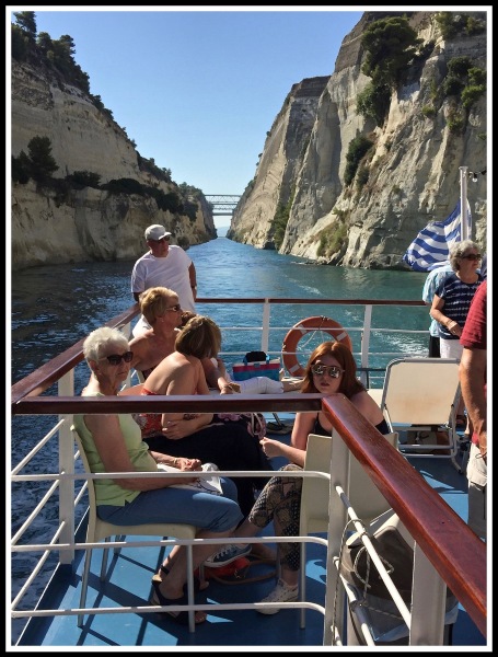 Photo of rear of boat showing people sat looking down Corinth canal.