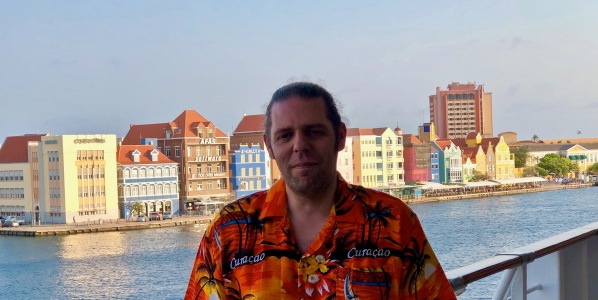 Me stood in front tof the colourful Curacao buildings wearing a Curacao orange shirt