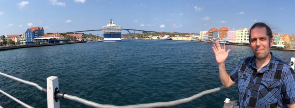 Me stood on the right of a panorama with the boat in the centre and the colourful buildings behind me.