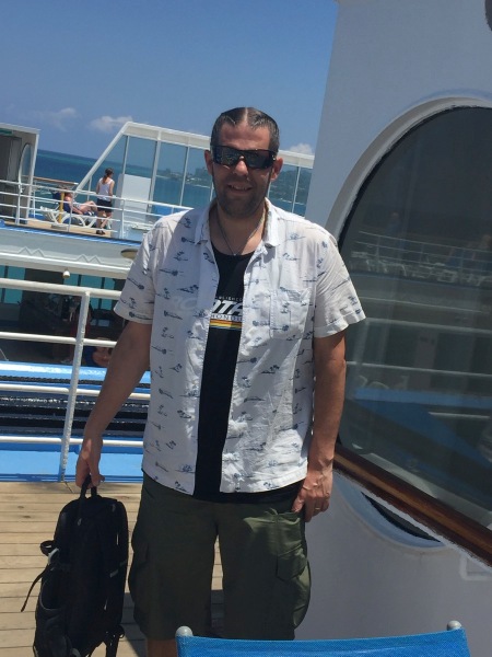 Full shot of me looking at the camera with shades on stood on the deck of the ship