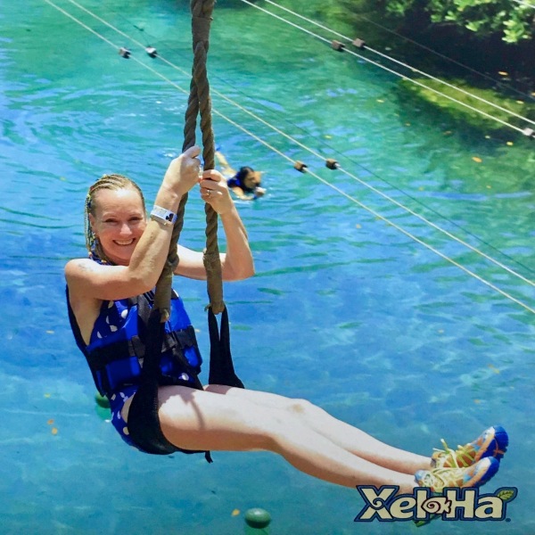 Sarah sat on a zip line seat going left to right with a big smile on her face