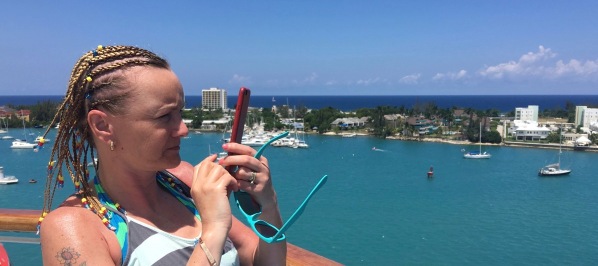Sarah with braided hair taking a panorama for the deck of the ship and the jamaican landscape in the background